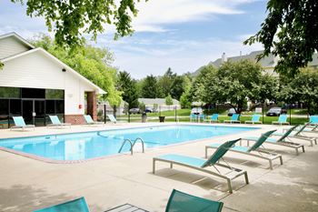A pool with sun loungers and a building in the background.
